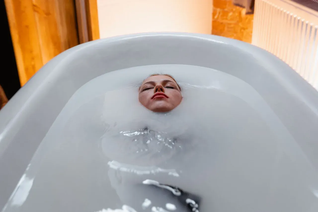 Persona relajada dentro de una bañera preparándose para un baño de hielo en casa
