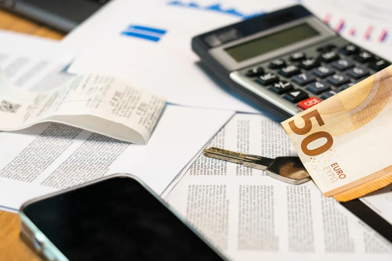 Calculadora y billetes de euro sobre documentos para calcular el coste real de un baño de hielo