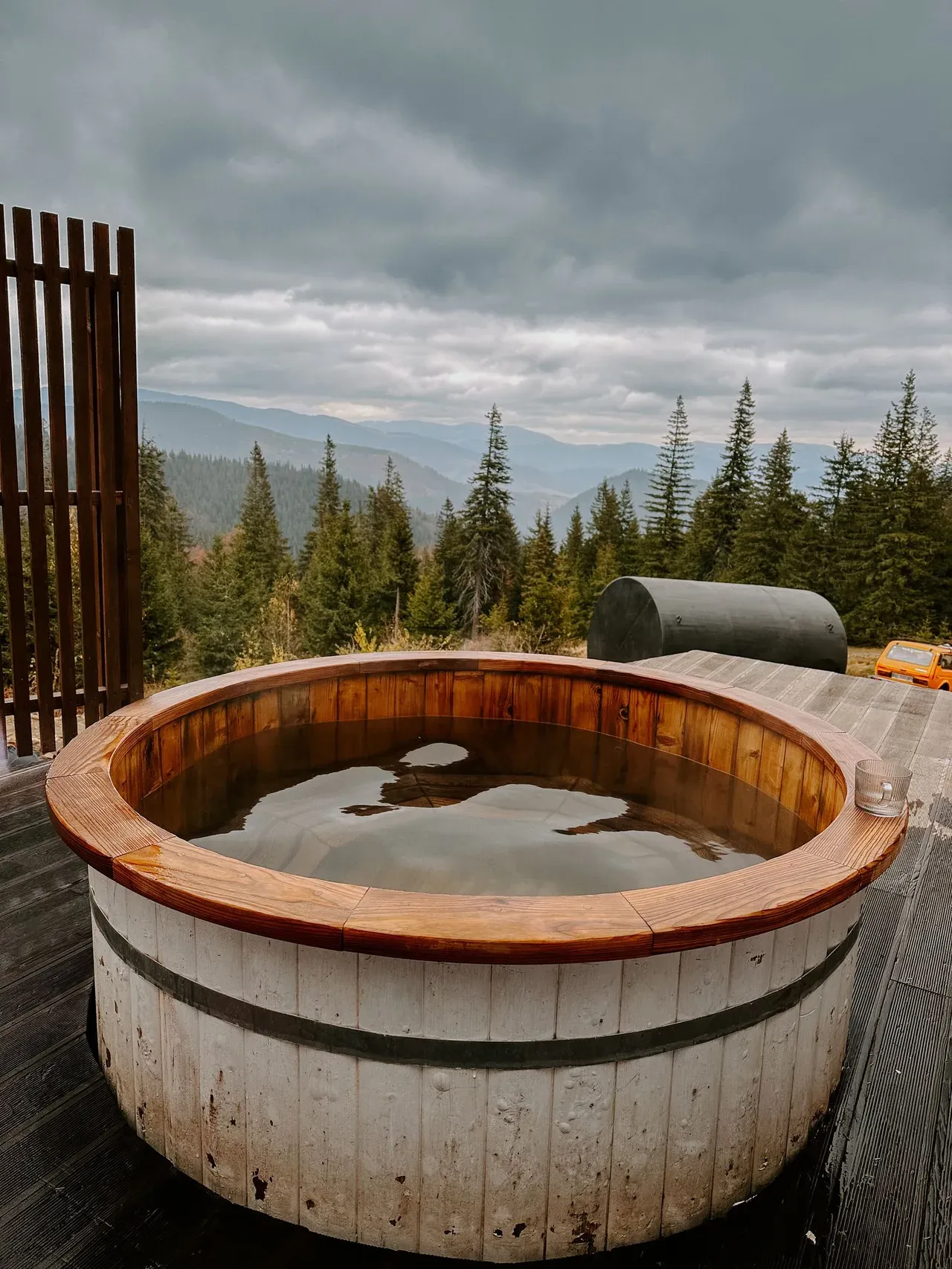 Tina de madera para baños de frío instalada en una terraza exterior con vistas al bosque