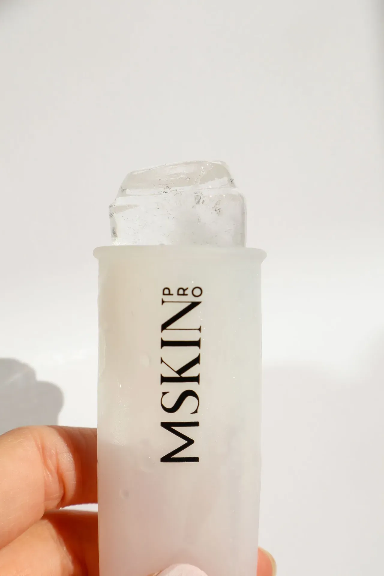 Rodillo de hielo para crioterapia facial junto a productos de cuidado de la piel