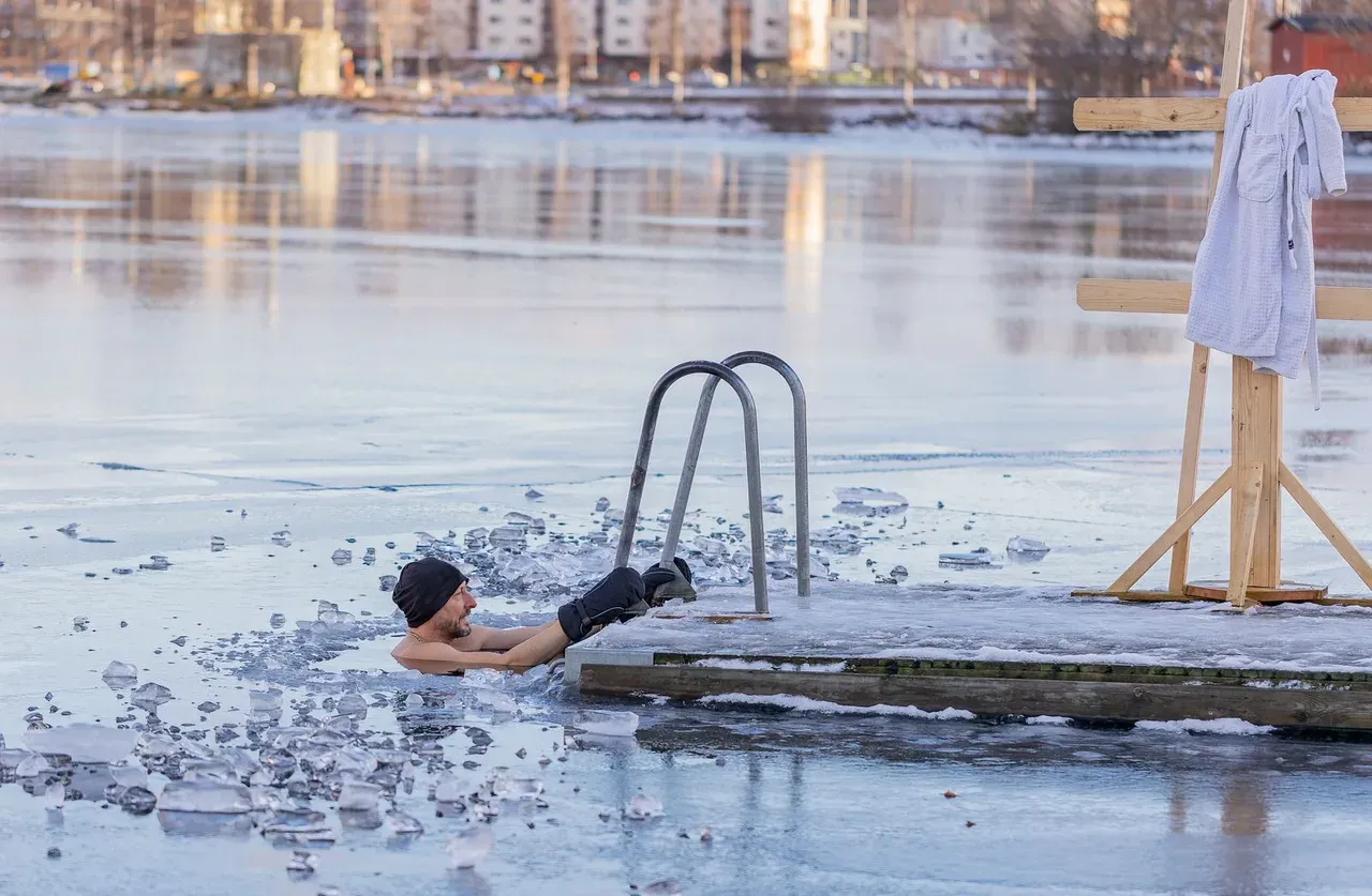Hombre sumergido en un lago helado durante una exposición al frío en invierno