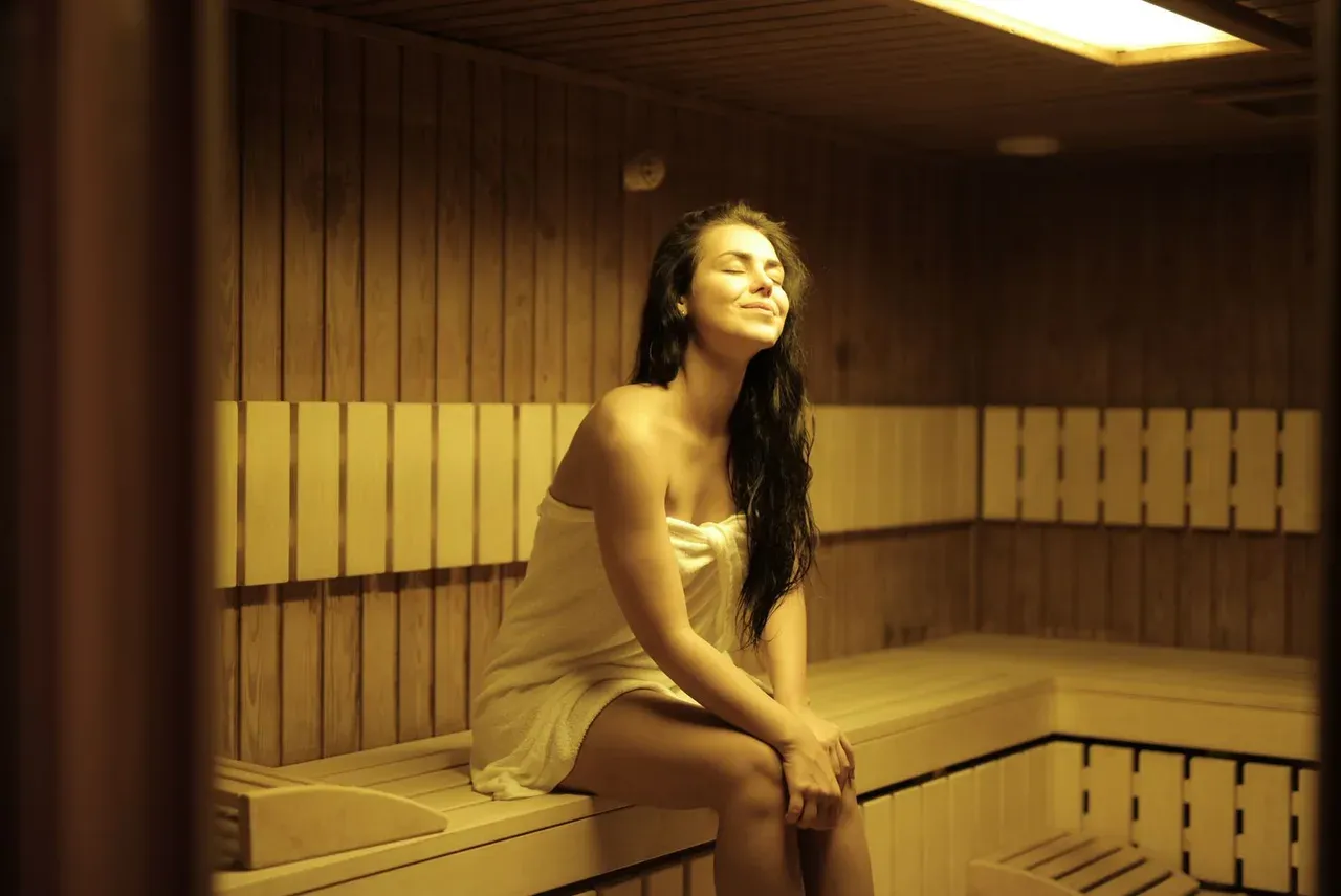 Mujer relajándose durante una sesión de sauna envuelta en una toalla